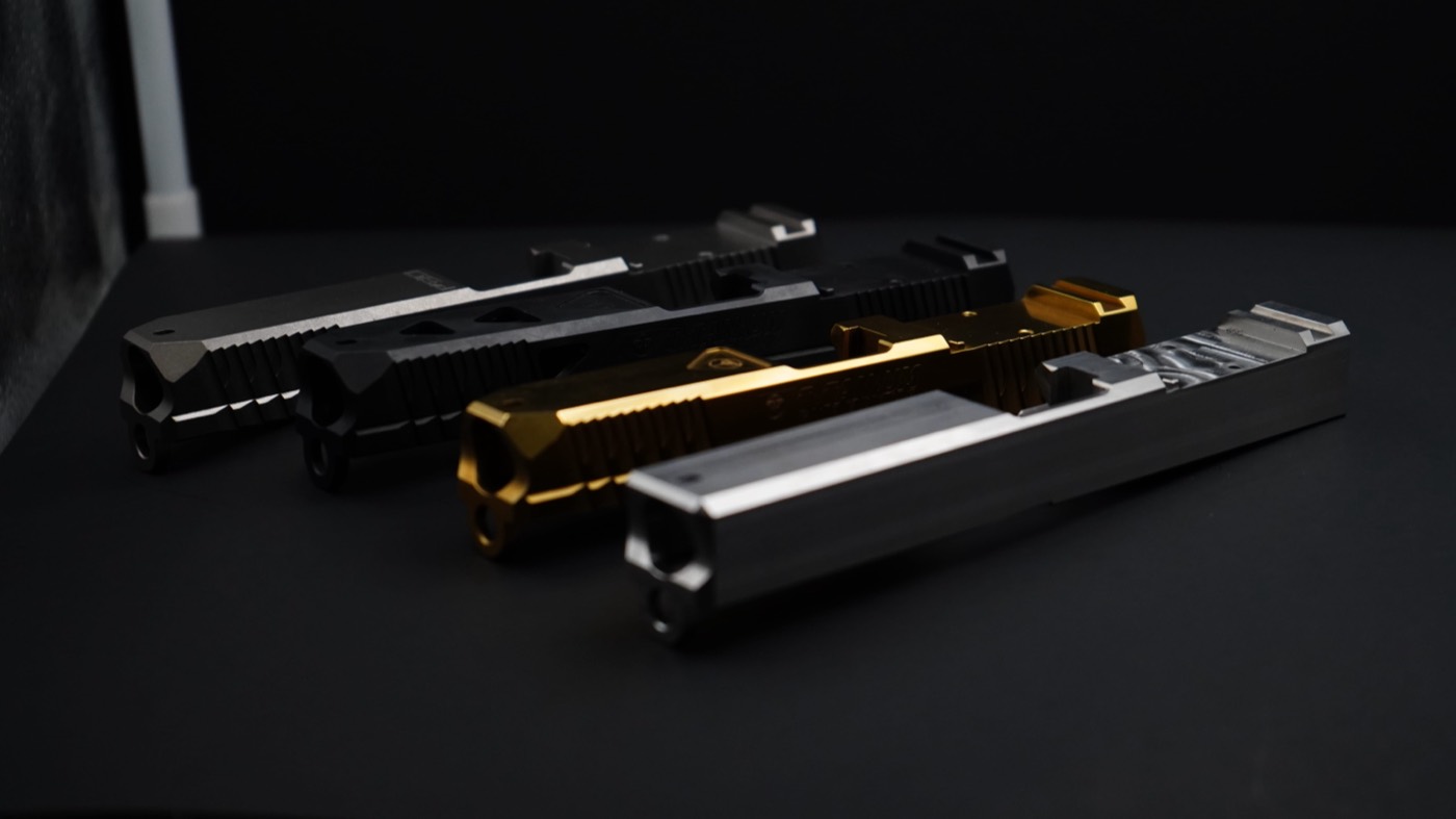 Row of PVD-coated Glock slides in black, gold and titanium grey